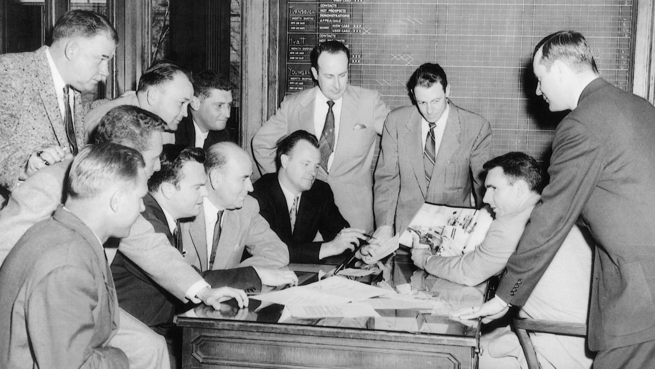 Jack Taylor meets with several team members in the late 1950s