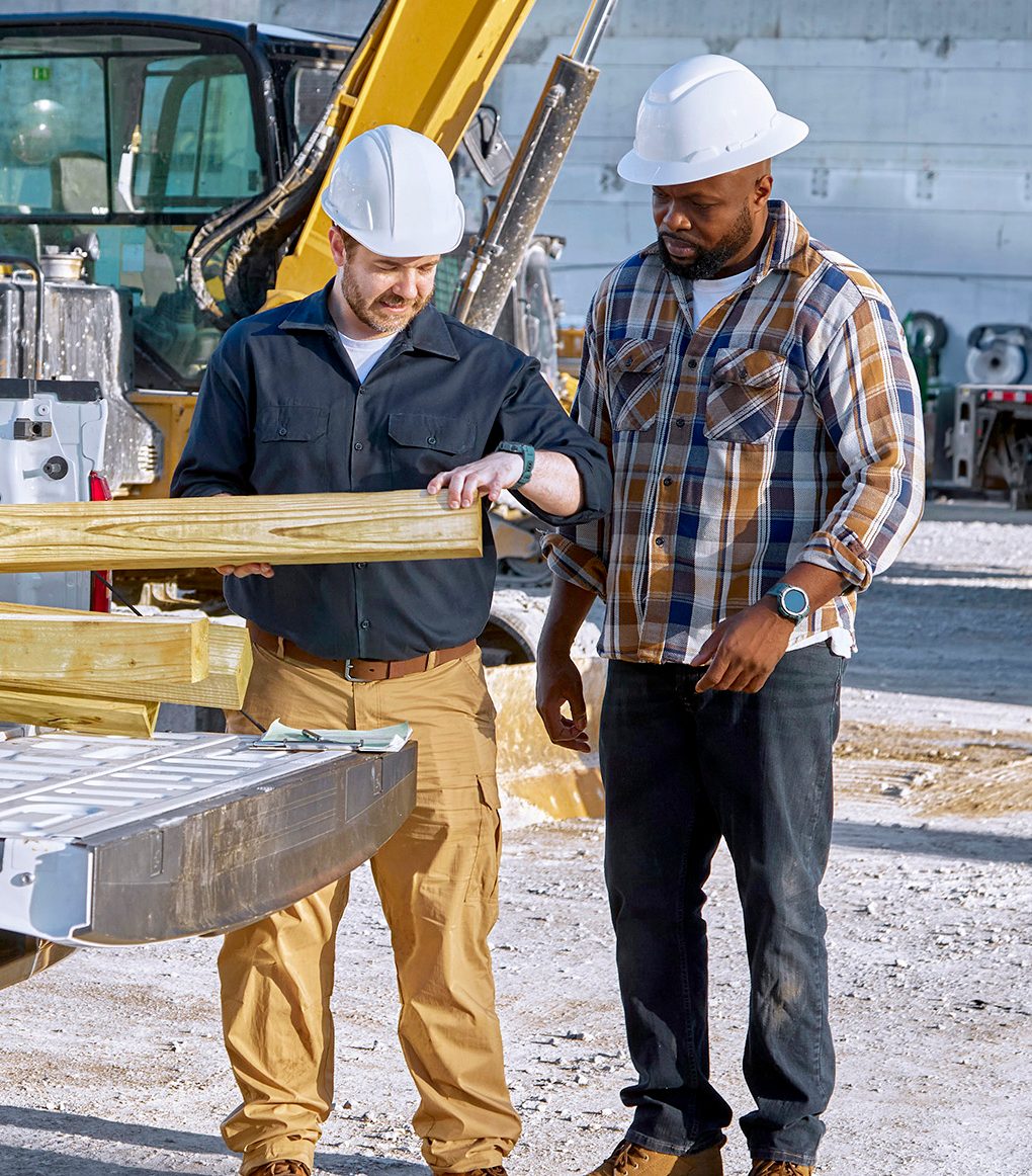 Two suppliers pull wood from a white pick-up truck
