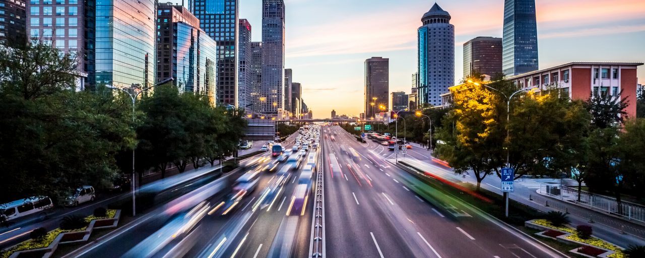 Image of a road with fast cars in a downtown setting