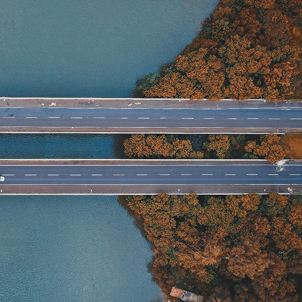 An aerial shot of a winding road with lots of green trees on both sides of it.