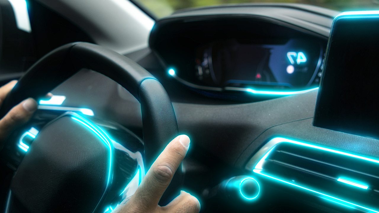 Hands on a wheel inside a car with neon blue lights