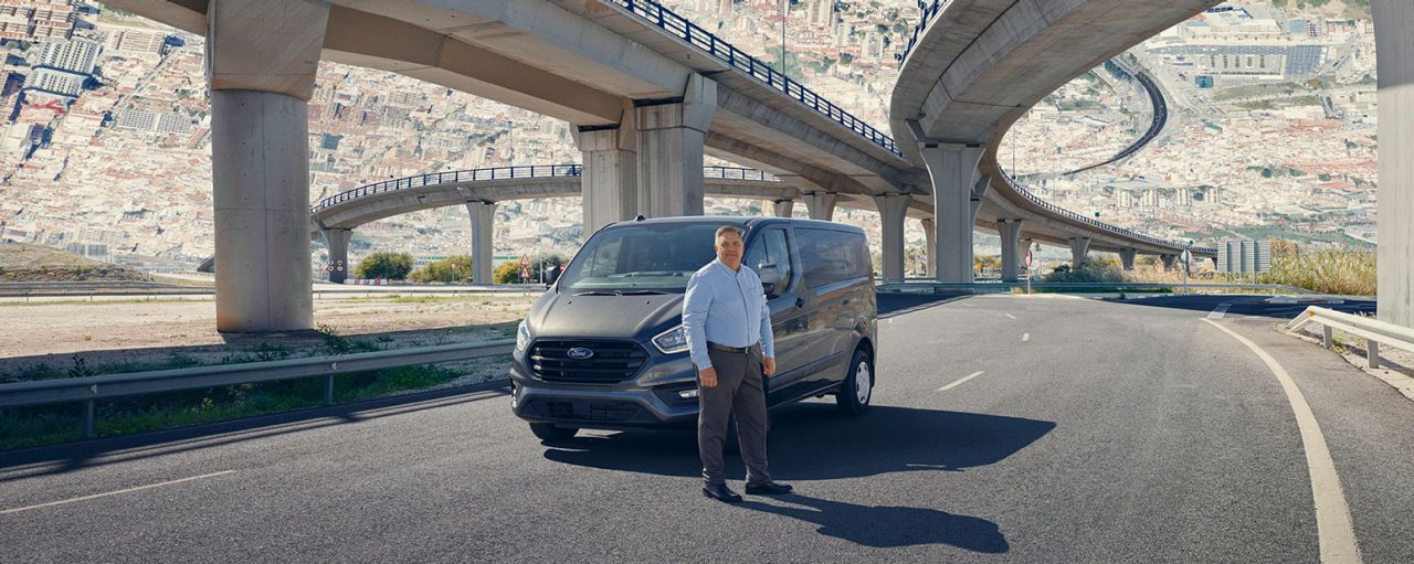 Man standing in front of a car on the interstate.