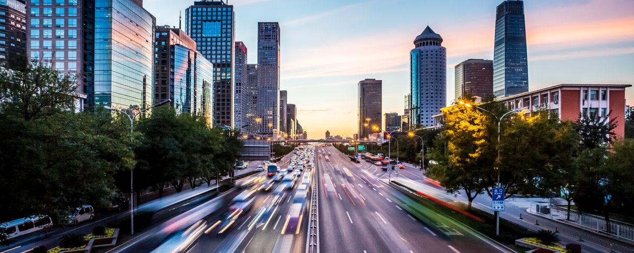 Image of a road with fast cars in a downtown setting