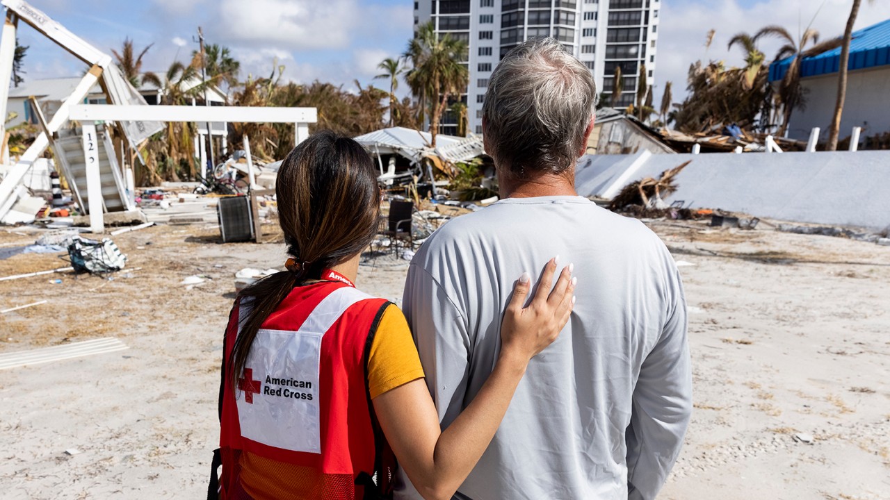 A man and woman with their backs to the camera look at a natural disaster
