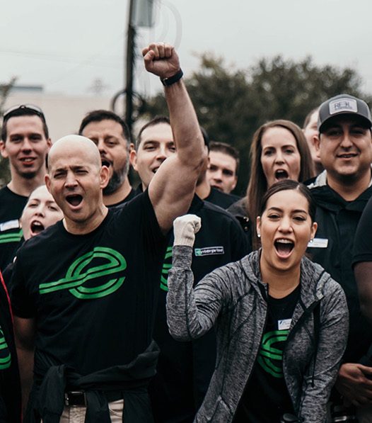 Several excited team members in black Enterprise shirts pumping their fists