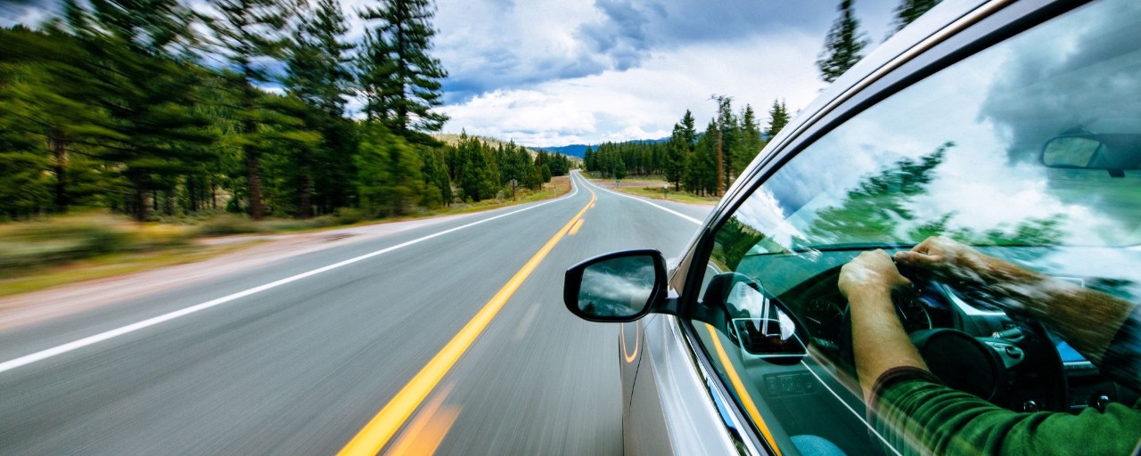 Hero image graphic for sustainability reporting page with car driving on a country road.